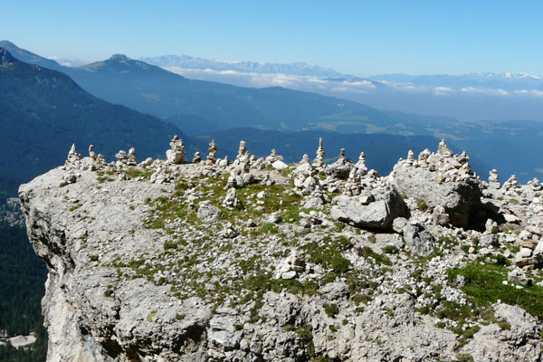 Turyści w Dolomitach lubią układać kopczyki, w tle na horyzoncie Alpy.